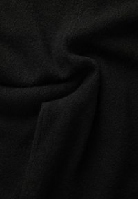 Zwarte stof met een zachte, gestructureerde oppervlakte, die subtiele plooien en een lichte glans vertoont, kenmerkend voor een warm materiaal zoals fleece of wol.