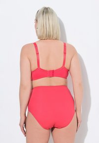 Röd bikini-set med en design med justerbara band på ryggen, högmidjade trosor och mjukt, stretchigt tyg. Ingen mönster eller detaljer.