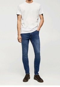 Bílá bavlněná tričko s krátkým rukávem spárované s modrými skinny džíny a hnědými šněrovacími botami. Jednoduchý design s vypasovaným střihem.