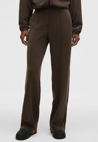 Pantalones de chándal marrones con un diseño de pierna recta, hechos de una tela suave. Presentan costuras sutiles para dar estructura y una cinturilla ancha para mayor comodidad.