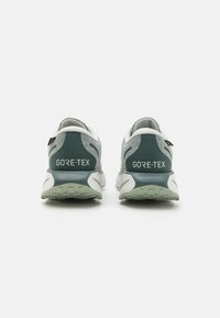 Buty biegowe GORE-TEX w jasnoszarym i turkusowym kolorze, z siateczkową cholewką, amortyzowaną podeszwą i markowym wykończeniem na pięcie.