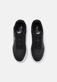 Mustat urheilukengät, joissa on sileä synteettinen pinta, rei'itetyt yksityiskohdat, pyöreä kärki, nauhat ja valkoinen kumipohja. PUMA-logomerkki näkyvissä.