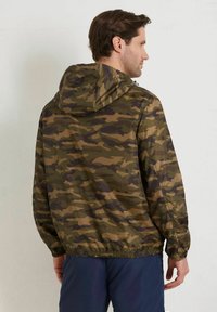 Kamouflagejacka i gröna och bruna nyanser, tillverkad av lätt material med justerbar huva och elastisk nederkant. Observera: lätt glans på tyget.