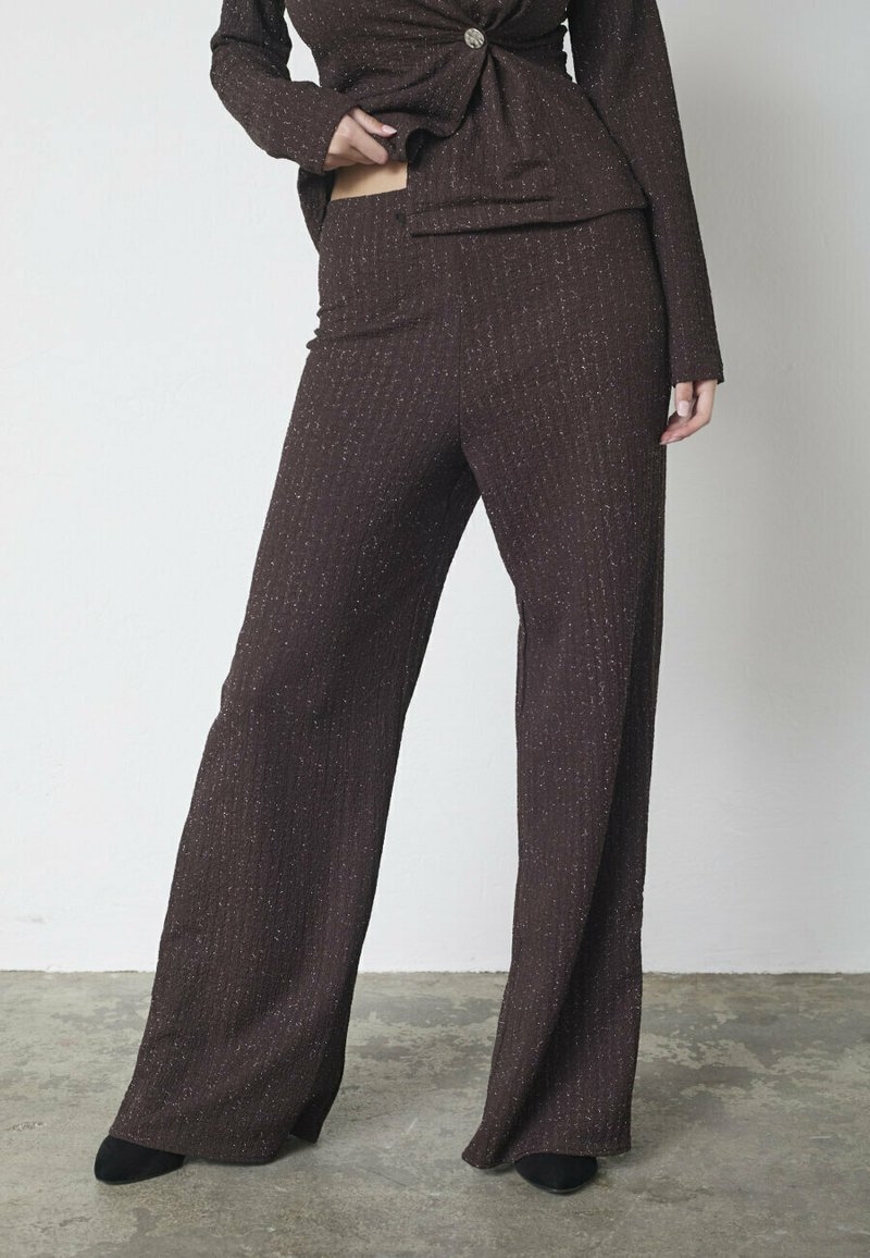 Brunt ribbet todelt sæt med en tætsiddende top med knudedetalje foran og vidde benbukser, begge med diskrete glitrende accenter.