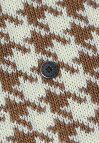 Tkanina dziana z brązowo-białym wzorem pepitki, z czarnym okrągłym guzikiem oznaczonym napisem "Burlington The Original".