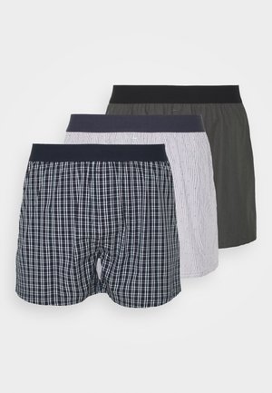 Drei Paare Boxershorts: eines mit schwarz-weißer Karomuster, eines mit feinen Streifen in Weiß und Rot und eines in einfarbig dunklem Grün. Alle verfügen über elastische Taillenbänder.