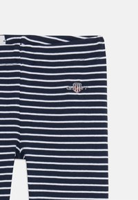 Navy in bele prugaste legice iz mehkega bombaža. Opremljene so z izvezenim logotipom na levi nogi in elastičnim pasom.