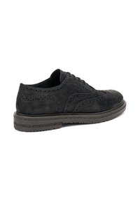 Scarpa oxford in suede nero con dettagli decorativi in brogue, dotata di una suola in gomma resistente e lacci, vista da un angolo.