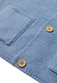 Cardigan lavorato a maglia azzurro chiaro con due tasche a toppa, dotato di bottoni in legno e un motivo testurizzato su tutto il tessuto.