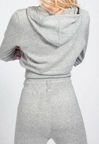 Šedá mikina s kapucí a texturovaným povrchem, s kapucí a žebrovaným lemem, doplněná o sladěné šedé tepláky. Jednoduchý, neformální design.