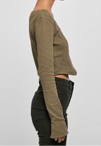 Oliivivärvi cropped pikki varrukas topp latex, millel on laia kaelus ning see on valmistatud tekstureeritud kangast. Omab kitsendatud varrukaid ja sirget äärt.