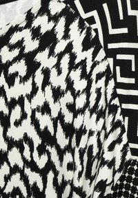 Black and white textile featuring two patterns: one abstract with curved shapes, the other geometric lines, both with varying textures.