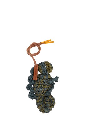 Häkeltes Seepferdchen in grünen und blauen Tönen mit einer strukturierten Oberfläche. Verfügt über eine braune Schnur und gelbe Plastikclips sowie ein Etikett.