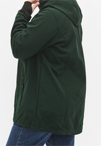 Groen gewatteerd jack met een gladde textuur, ritszakken en een losse pasvorm. Voorzien van een donkere voering aan de binnenkant en detaillering aan de zijnaden.