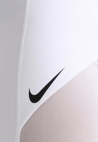 Pantalones cortos deportivos blancos con un logotipo negro de Nike Swoosh. La tela tiene una textura suave con un panel de malla para mayor transpirabilidad.