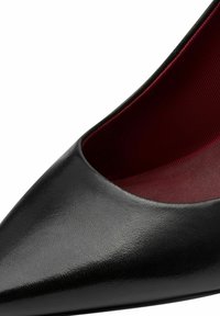 Black high-heeled shoe with a pointed toe design, made of smooth leather, and a red satin interior lining.