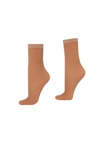 Ljust tan ankelsockor med ribbad manschett, tillverkade av ett slätt, stretchy material som har ett subtilt texturerat mönster över ytan.