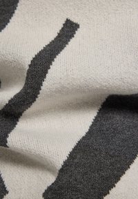 Strickstoff mit einem wellenförmigen Muster in Schwarz und Hellgrau. Die Textur ist weich, mit sichtbaren Maschen und dezenten Farbabweichungen.