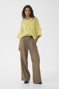 Πλεκτό πουλόβερ σε λάιμ πράσινο με υφή και κλείσιμο με κουμπιά, συνδυασμένο με καφέ ψηλόμεσο παντελόνι με φαρδιά πόδια και καφέ ζώνη.