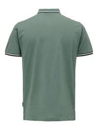 Polo vert à manches courtes avec col et poignets rayés blancs et noirs, vu de dos sur fond blanc.