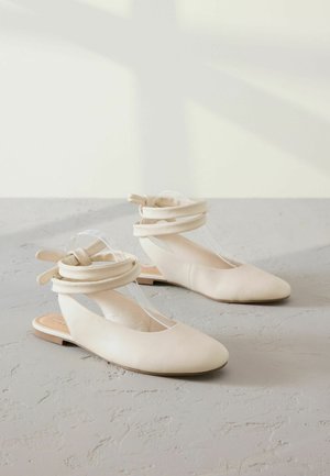 Bežīgas kurpes ar noapaļotu purngalu, mīkstu ādas materiālu un caurspīdīgo siksniņu dizainu. Rievotas malas ar sasietiem akcentu detaļām. Plakana zole.