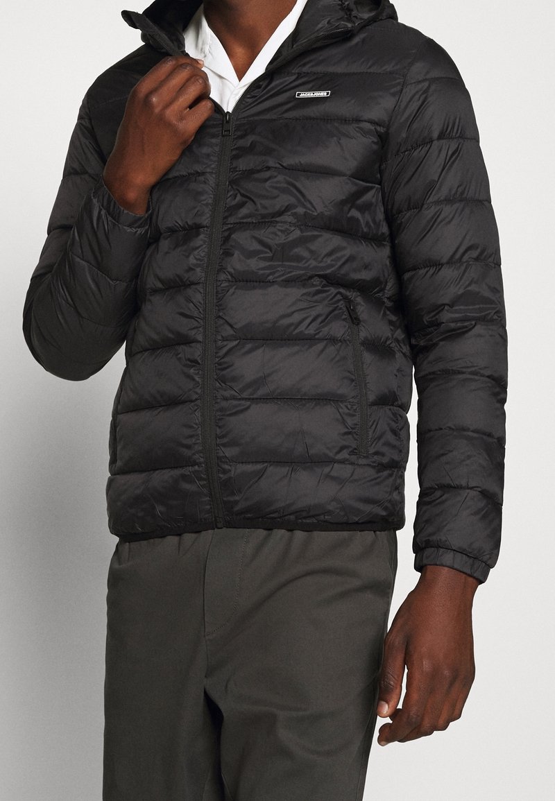 Czarna kurtka puchowa z zamkiem z przodu, poziomym pikowaniem, kapturem i bocznymi kieszeniami; gładka faktura i lekki materiał.