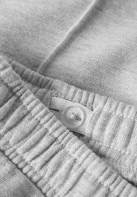 Szara tkanina o miękkiej fakturze, z marszczonym paskiem w talii i zapięciem na plastikowy guzik. Materiał ma subtelny połysk.