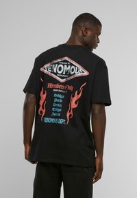 Sort kortærmet T-shirt med et stort, farverigt grafisk motiv på ryggen med flamdesigns og bynavne i blå, rød og hvid tekst.