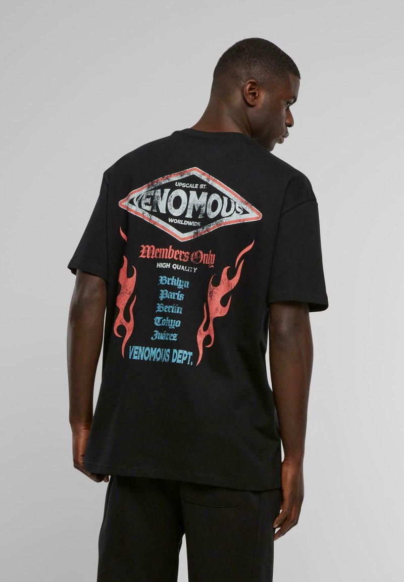 Sort kortærmet T-shirt med et stort, farverigt grafisk motiv på ryggen med flamdesigns og bynavne i blå, rød og hvid tekst.