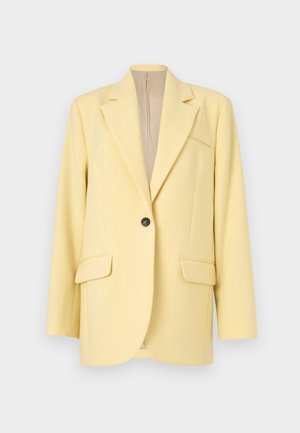 Blazer jaune pâle à un bouton avec revers crantés, deux poches à rabat à l'avant et une poche poitrine passepoilée, présenté sur un fond neutre.