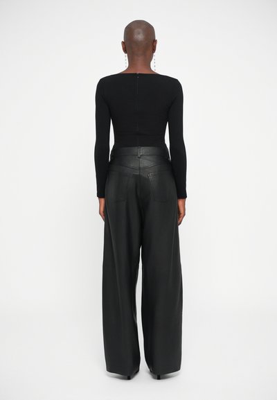 Top negro de manga larga con escote cuadrado, combinado con pantalones de cuero negros de pierna ancha y cintura alta que cuentan con bolsillos traseros y costuras.