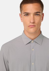 Camicia a righe grigia e bianca, con colletto classico e vestibilità regolare, caratterizzata da una texture liscia e un motivo sottile.