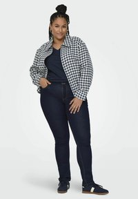 Marynarka w wzór houndstooth w kolorze granatowym i białym, połączona z granatową bluzką i ciemnymi rurkami, noszona z granatowymi trampkami z kremowym paskiem.