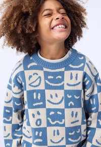 Strickpullover mit einem Blockmuster aus verschiedenen Smileys in Blau- und Cremetönen. Rundhalsausschnitt, strukturiertes Material, verspieltes Design.