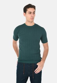 Maglione verde a maniche corte, a coste, con scollatura rotonda e design aderente, abbinato a pantaloni in denim scuro con coulisse.
