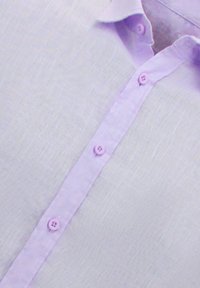 Licht lila shirt gemaakt van textuurstof met een knopenlijst met lila knopen en een klassieke kraag.