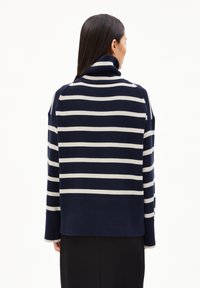 Pull en maille rayé marine et crème avec un col montant, une coupe décontractée, des manches larges, une texture côtelée et un ourlet légèrement court.