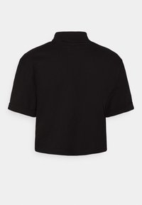 Svart kortärmad t-shirt i mjukt tyg, med korta upprullade ärmar och hög krage, med en slät, enfärgad yta.