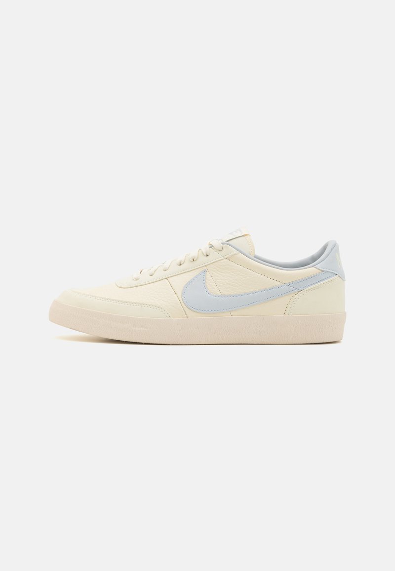 Tenisky Nike, béžový kožený zvršok s svetlomodrými akcentmi, okrúly špička, plochá gumová podrážka a šnurovanie. Textúrovaný povrch a hladký dizajn.