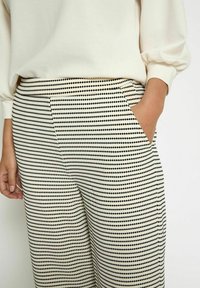 Wide-leg trousers in a cream and black striped pattern, featuring a smooth texture and side pockets for functionality.