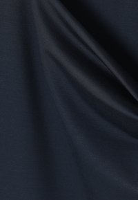 Κοντινό πλάνο από ύφασμα σκούρου ναυτικού μπλε με ομαλή υφή και ορατό σχέδιο ύφανσης, απαλά διπλωμένο για να δείξει φως και σκιά.