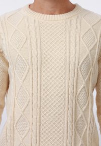 Pull en maille crème présentant divers motifs texturés, y compris des torsades et des losanges, avec un col rond côtelé.