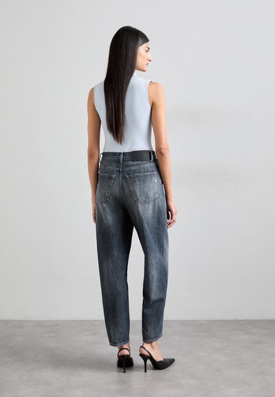 Lys blå ermeløs topp kombinert med mørkegrå høyt midje jeans. Jeansene har sidelommer og er lett smale ved anklene.