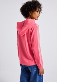 Felpa rosa con cappuccio, con strisce bianche lungo le maniche. Realizzata in materiale morbido, ha una vestibilità comoda e maniche lunghe.
