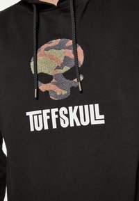 Fekete kapucnis pulóver, textúrált, színes koponya grafikával, alatta vastag fehér betűkkel "TUFFSKULL" felirattal. Részletes zsinórok.
