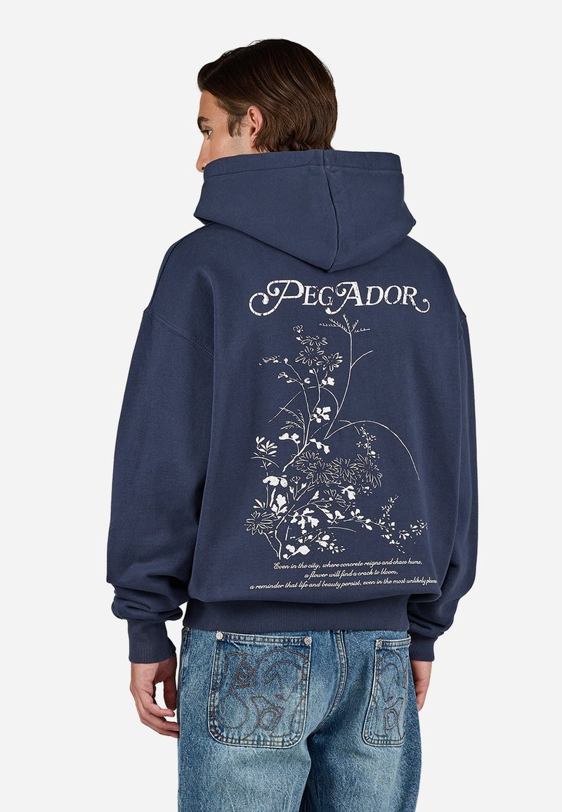 Marineblauwe hoodie met een groot bloempatroon en tekst op de achterkant. Voorzien van een koord in de capuchon en een losse pasvorm.