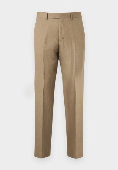 Μπεζ παντελόνια ραμμένα κατά παραγγελία με θηλιές για ζώνη, πτυχές μπροστά και εφαρμογή με ίσια πόδια σε απλό φόντο.