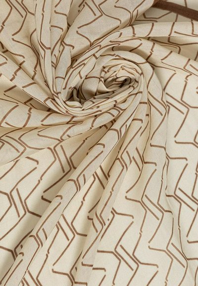 Tessuto beige chiaro con un motivo geometrico a zig zag marrone, disposto in una piega centrale a spirale.