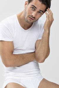 White short-sleeve T-shirt worn by a man, featuring a round neckline. Soft texture, smooth fabric, fitted design accentuating the torso.