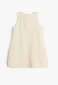 Sukienka bez rękawów w kolorze kremowym, z teksturowanej tkaniny o prostym fasonie. Posiada centralny zamek błyskawiczny z tyłu i brak dodatkowych ozdób.